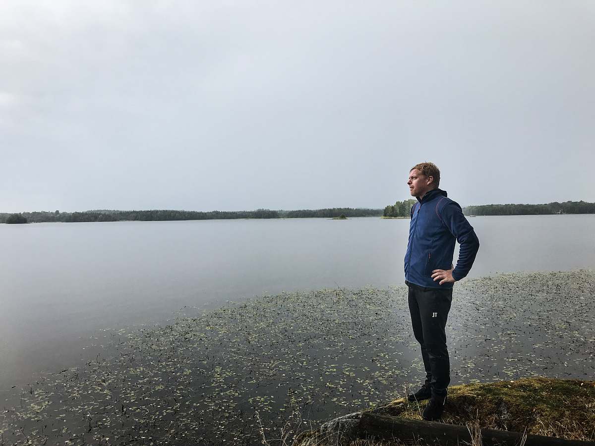 human man standing on cliff near body of water people