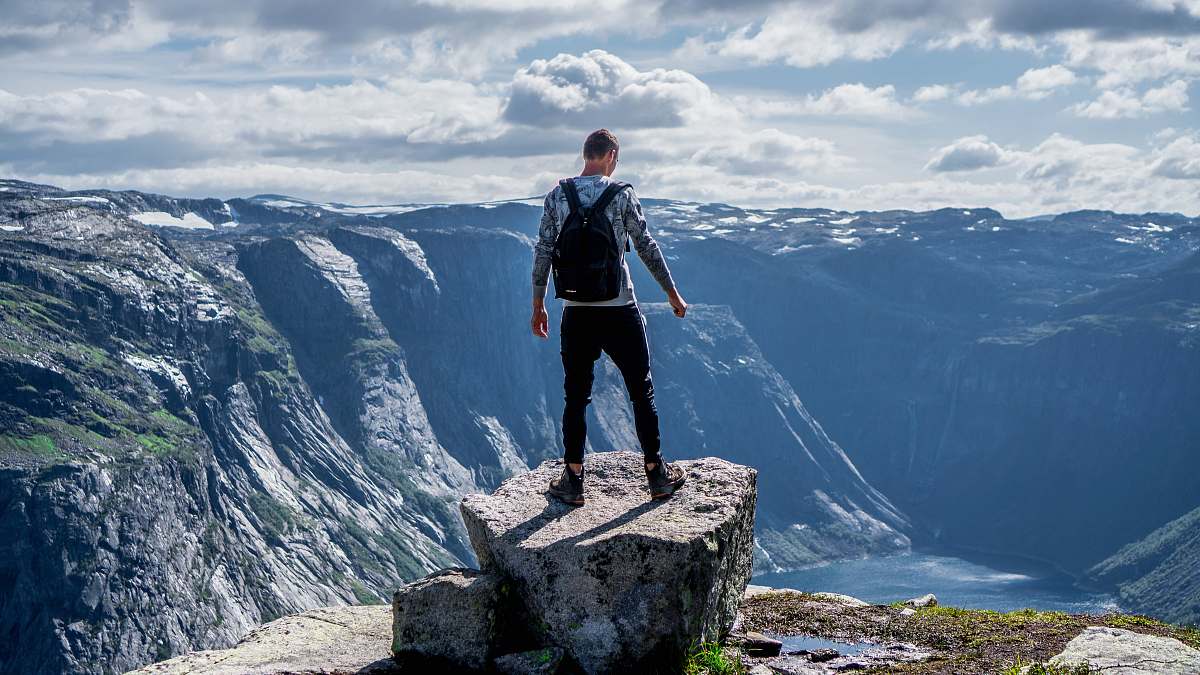 human man standing on edge of cliff mountain