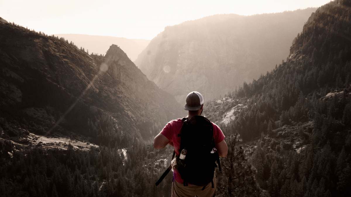 people man standing on elevated ground facing mountains during daytime human