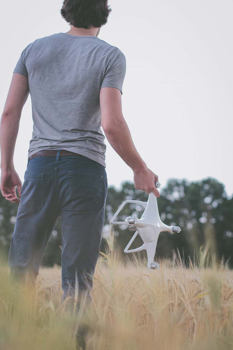 human man standing on field holding white quadcopter people
