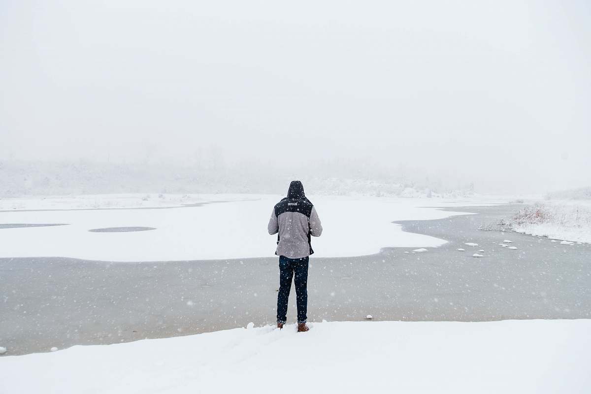 winter man standing on snow field facing river river