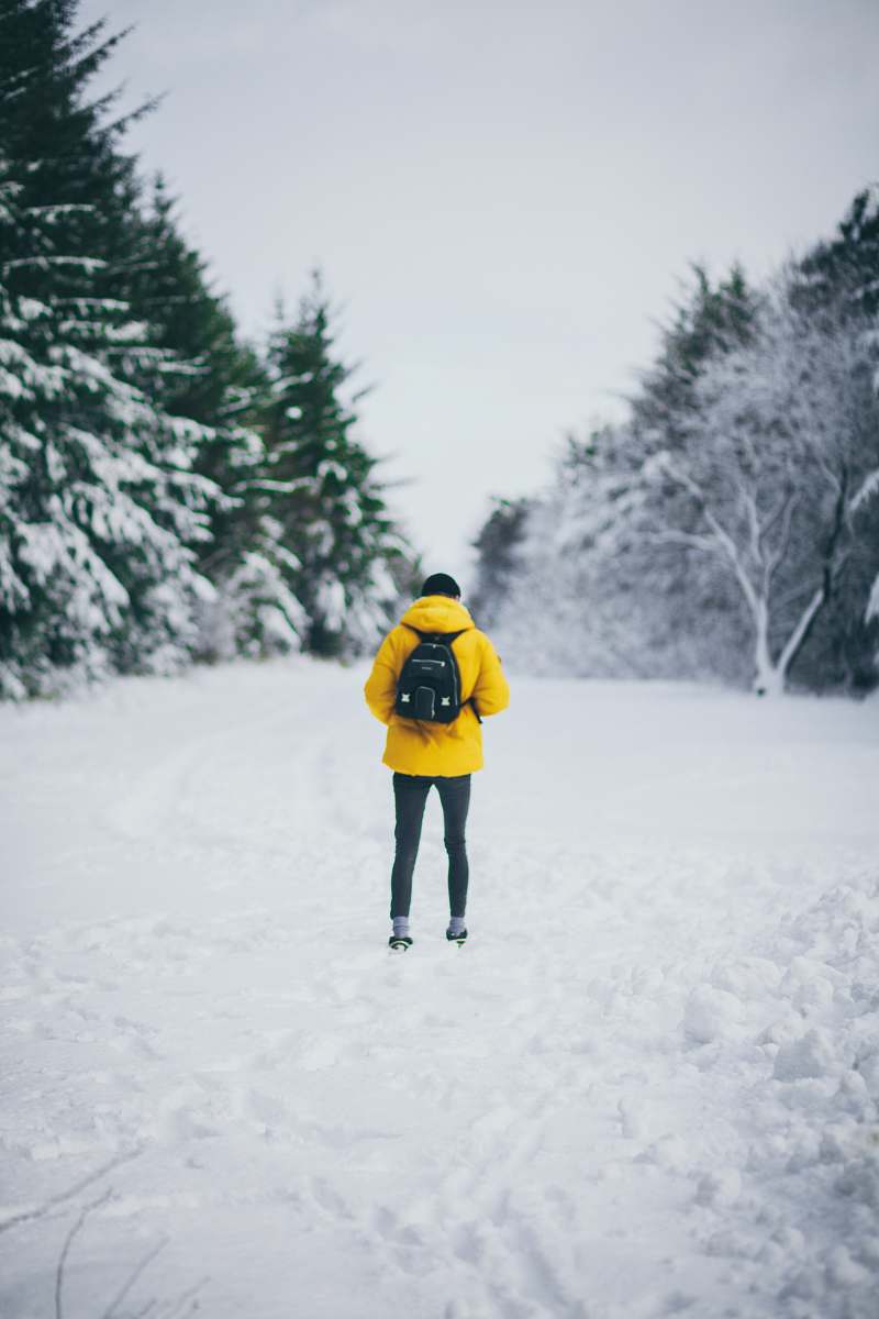 human man standing on snowfield while carrying backpack during daytime people