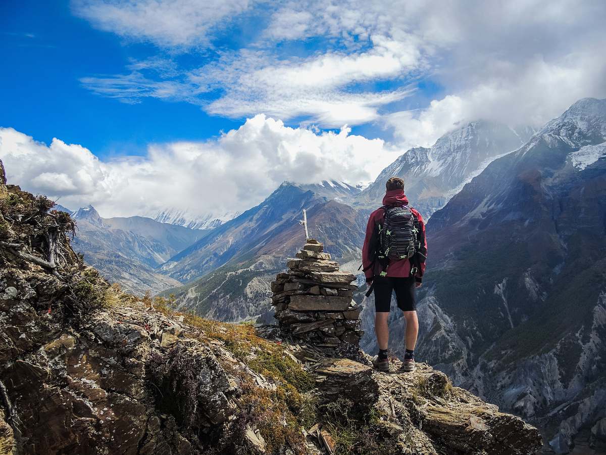 mountain man standing on top of mountain beside cairn stones mountain range