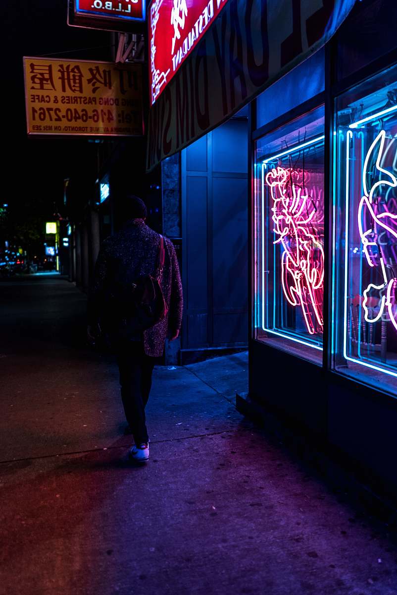 people man walking beside neon-lighted store taken at nigthttime human