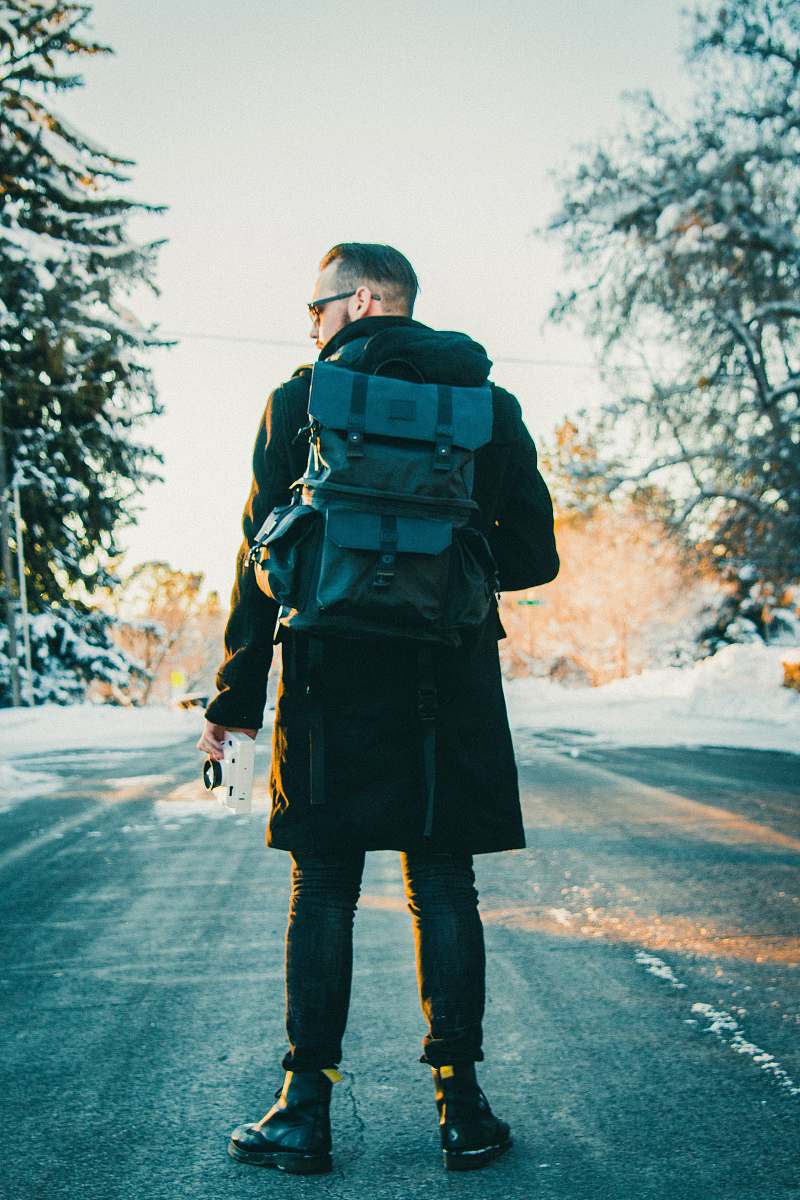 human man wearing backpack in middle of the road people
