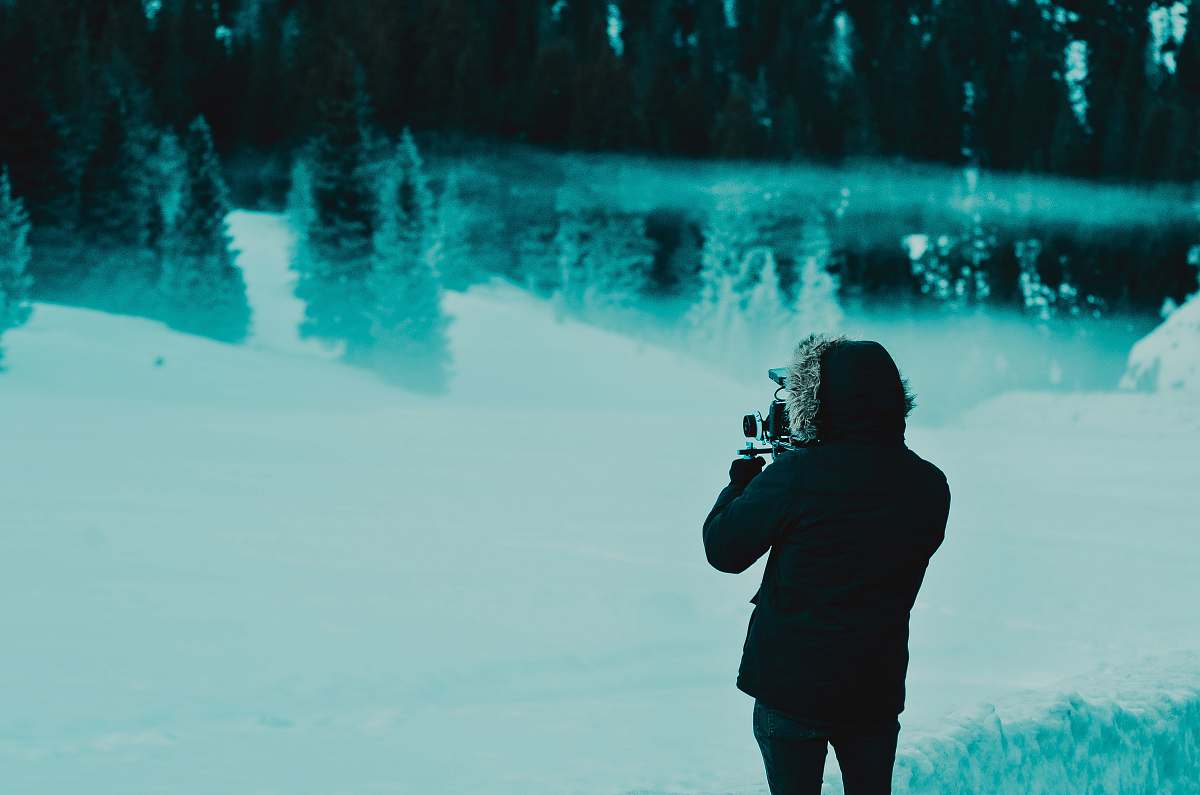 human man wearing black hoodie jacket while standing on snow covered pathway people