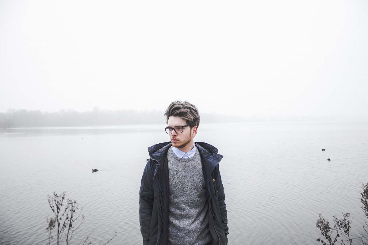 people man wearing black jacket standing near body of water human