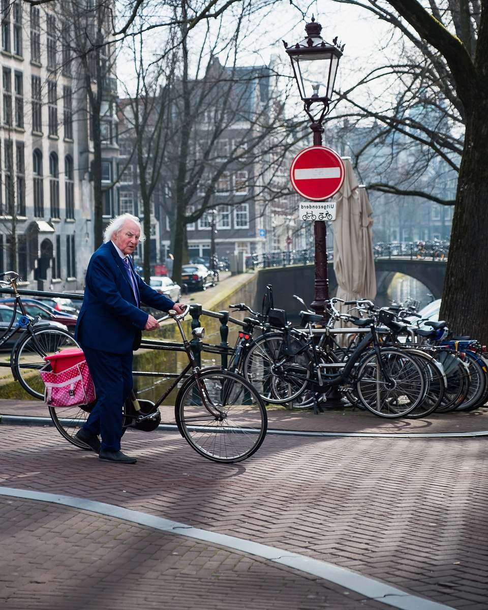 bicycle man wearing black notched lapel suit jacket holding bike bike