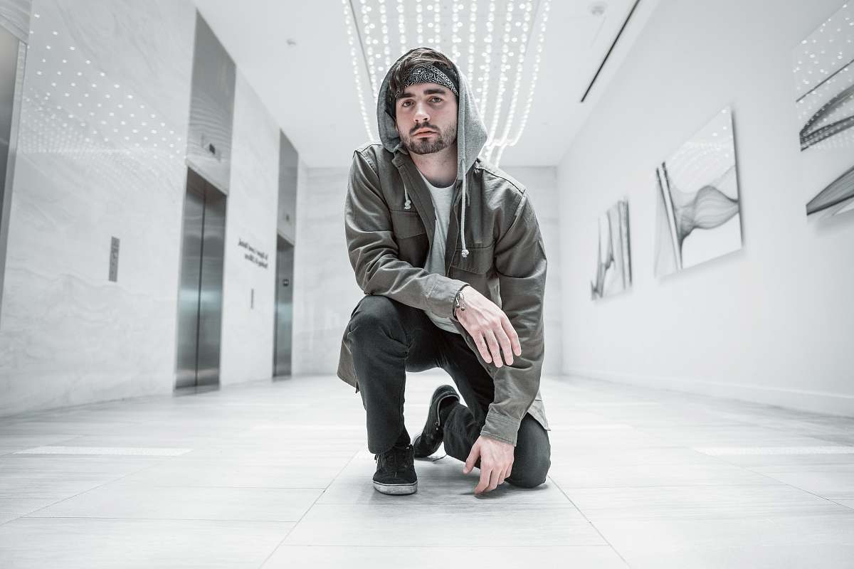 people man wearing black pullover hoodie while kneeing on white floor in room human