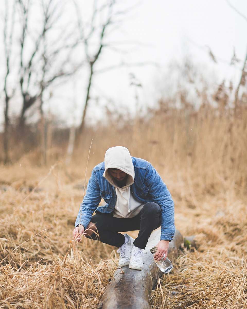 people man wearing blue denim jacket holding bottle human