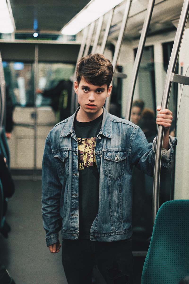 people man wearing blue denim jacket standing inside train human
