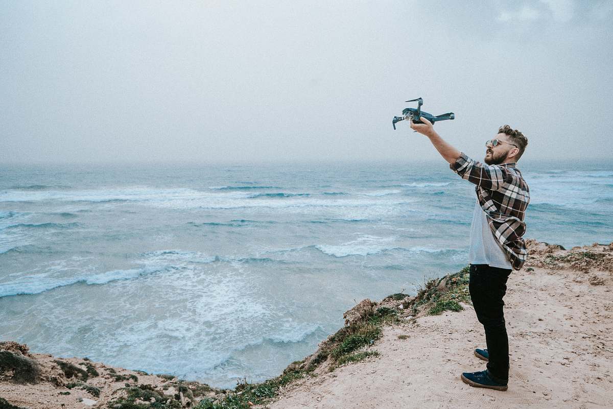 human man wearing brown, white and black plaid dress shirt near shore people