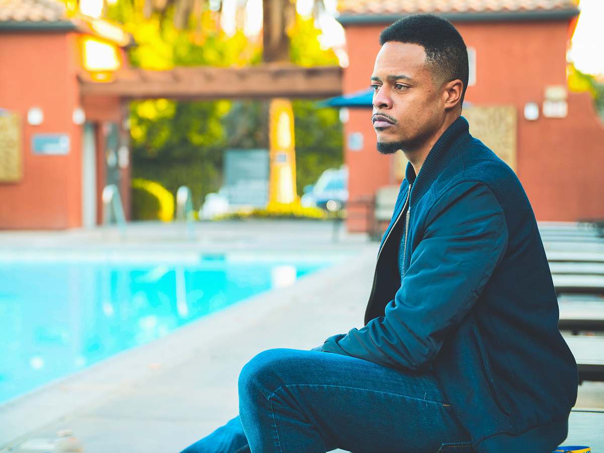 human man wearing dark-blue jacket sitting down near pool people