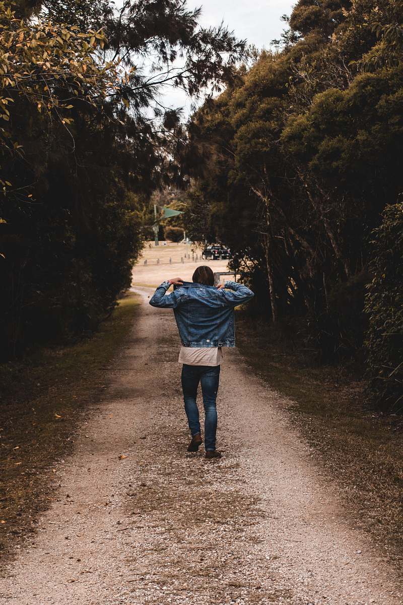 human person holding denim jacket while walking road