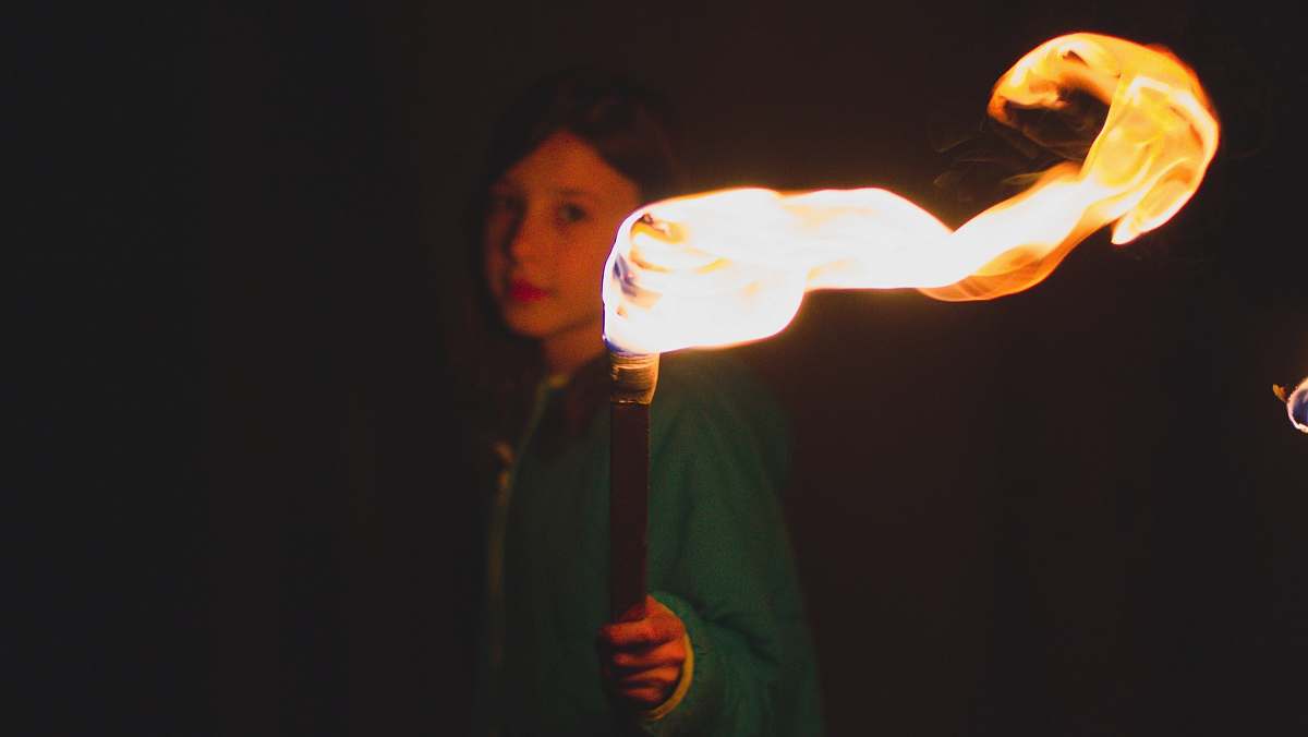 fire person holding torch during night time flame