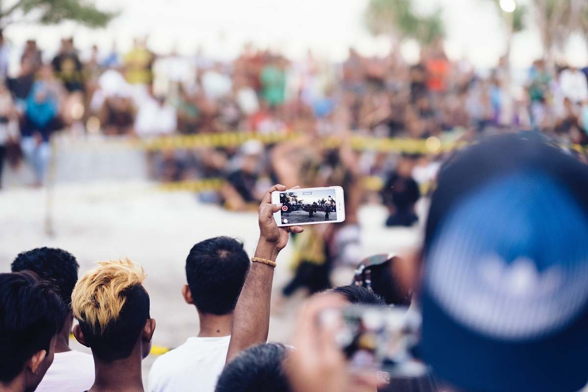 people person holding white smartphone while taking photo human