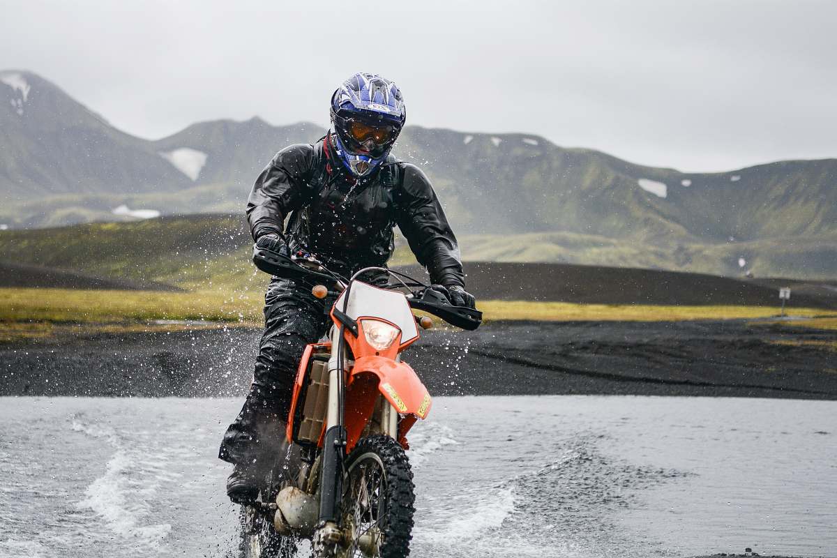 motocross person riding dirt motorcycle on body of water during daytime motorcycle