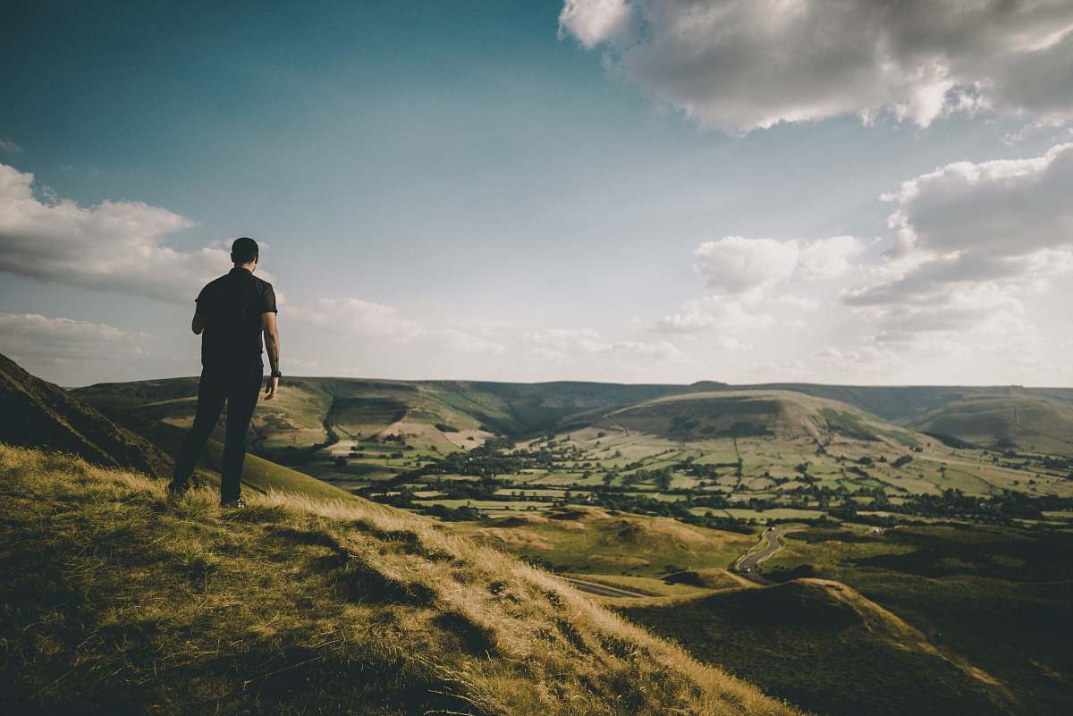 human person standing on hill during cloudy daytime people