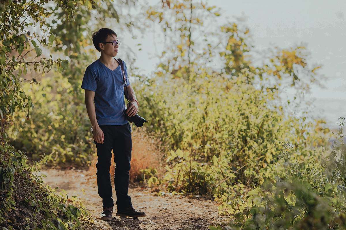 people person wearing shirt standing on forest with DSLR camera human