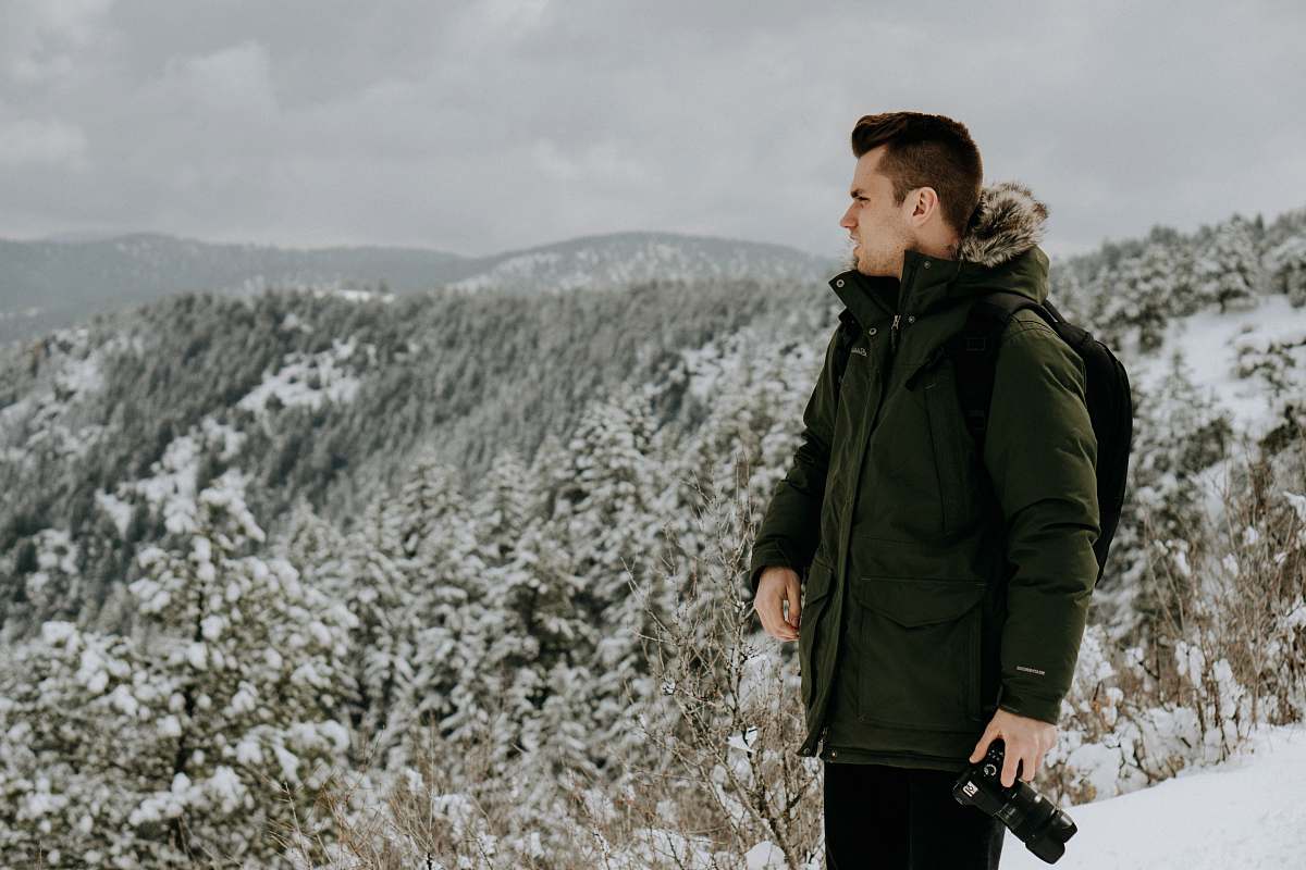 human photo of man wearing green jacket holding DSLR camera people