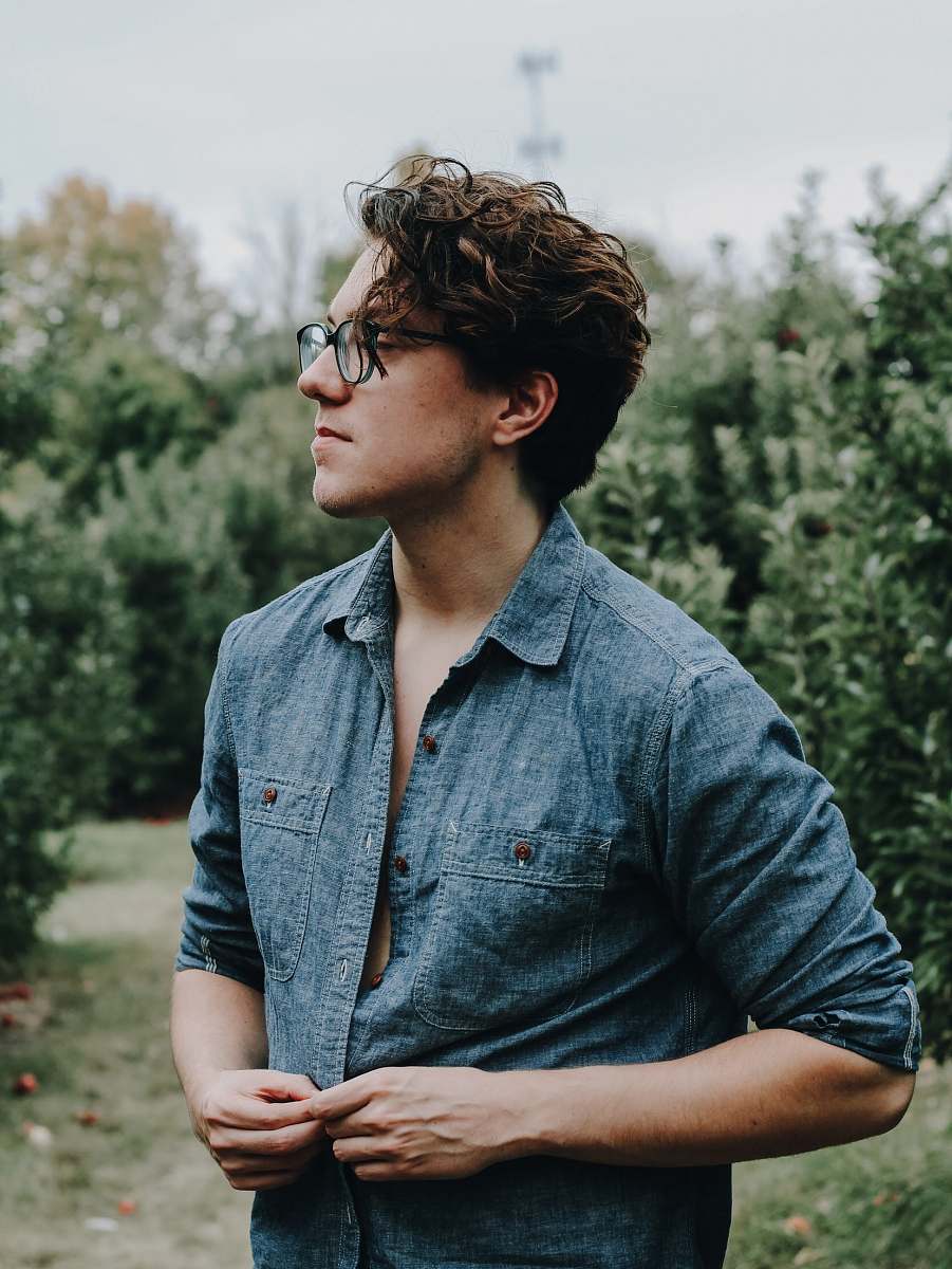 human selective focus photography of man holding his shirt button people