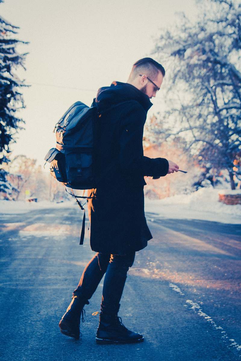 human selective focus photography of man in black coat carrying gray backpack people