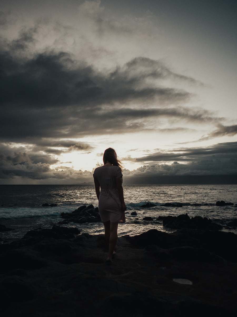 human silhouette photography of woman standing near sea waves people