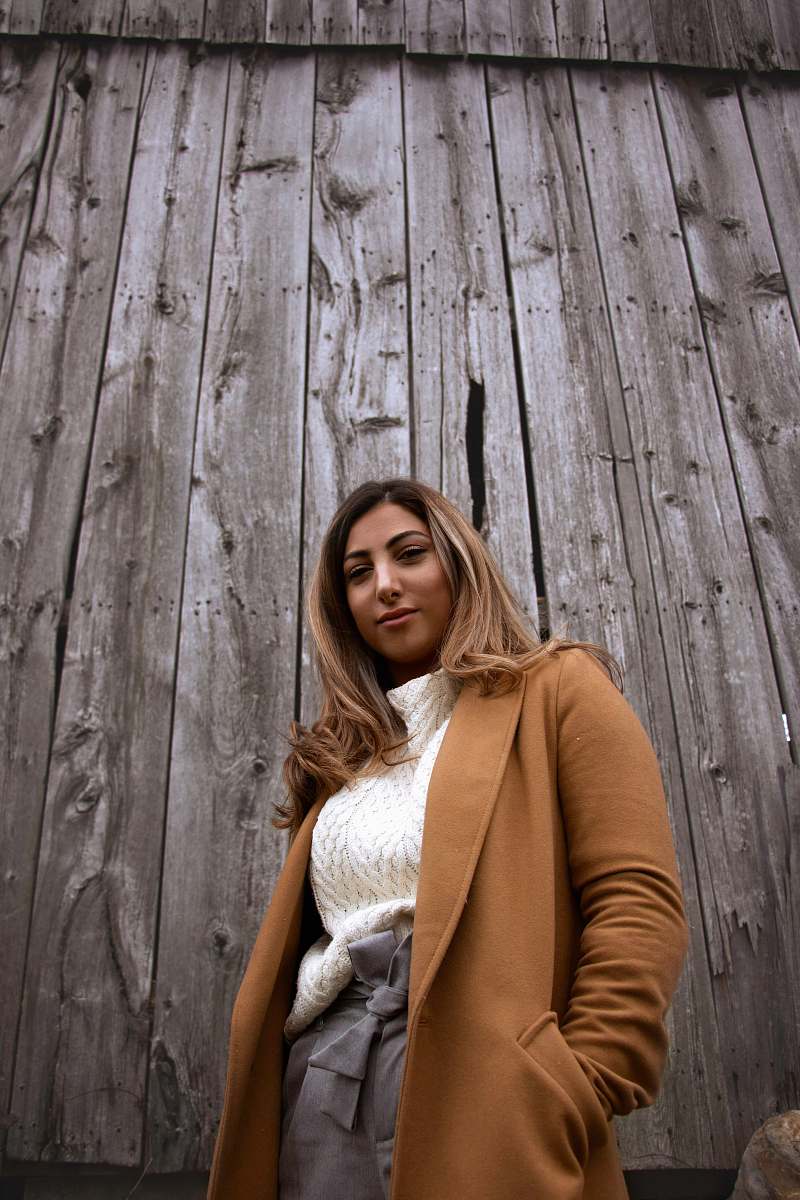 human smiling woman in brown coat by wooden panel people