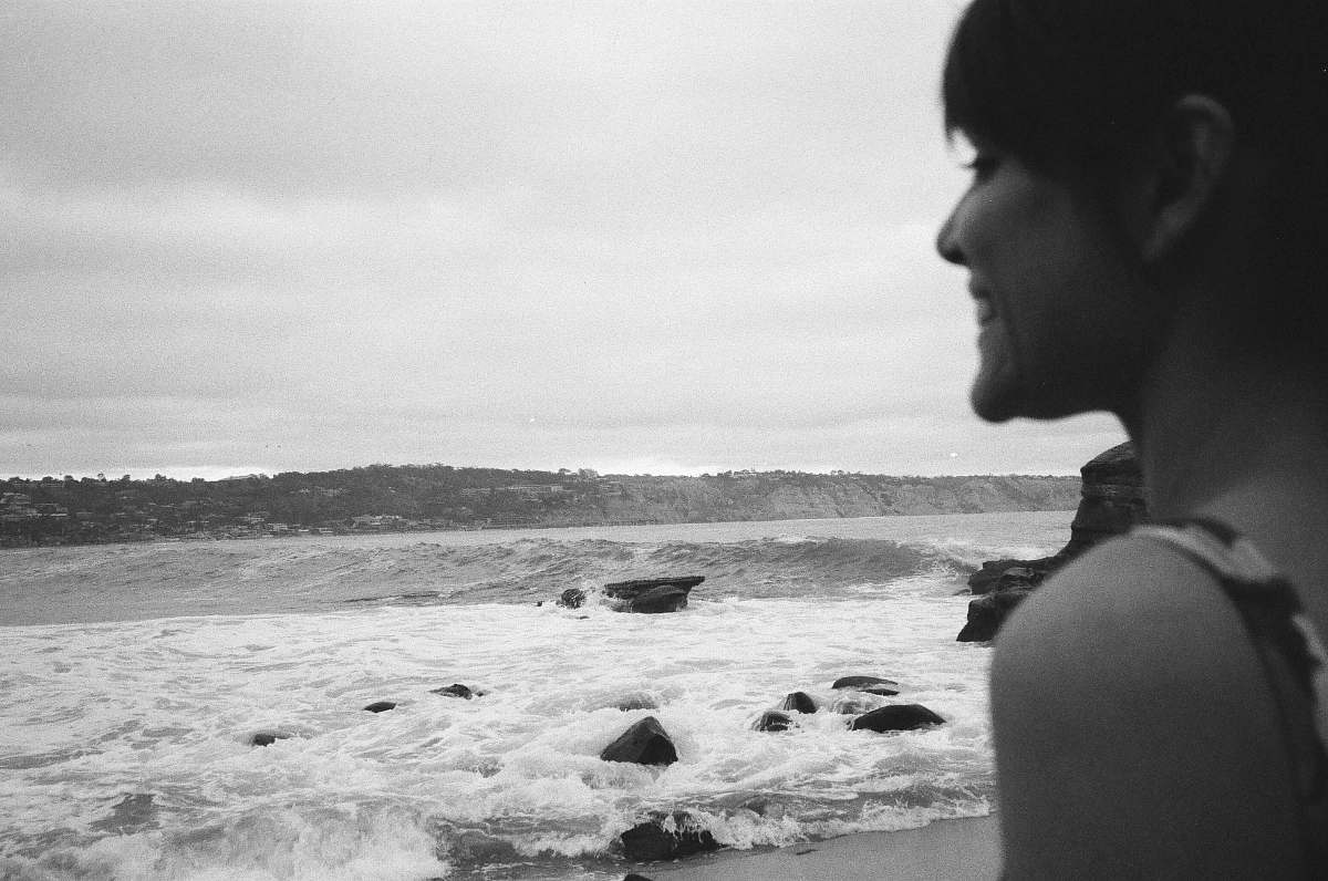 black-and-white smiling woman standing on front onf seashore grey