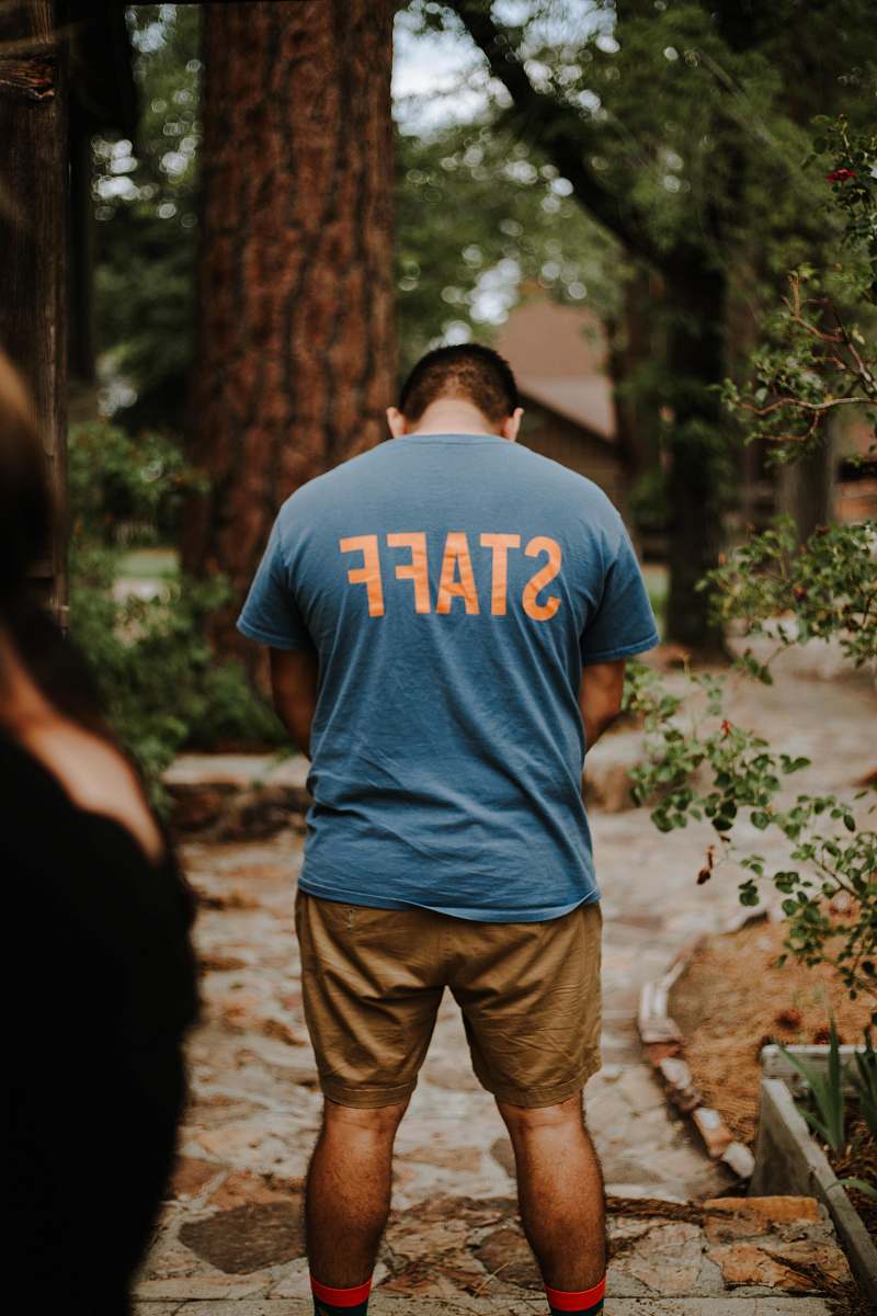human standing man wearing staff t-shirt near tree people