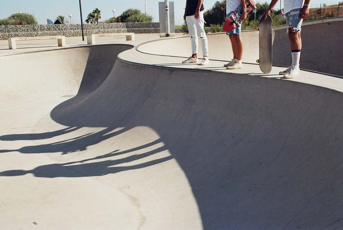 Capture the essence of urban sports with this vibrant image of three skaters confidently balancing on a skateboard atop a concrete ramp. Set against the backdrop of a lively skate park, the interplay of daylight and shadows adds depth to the thrilling atmosphere. Ideal for use in sports magazines, skateboarding blogs, and promotional materials for athletic events, this image embodies the spirit of adventure and camaraderie among skateboarding enthusiasts.