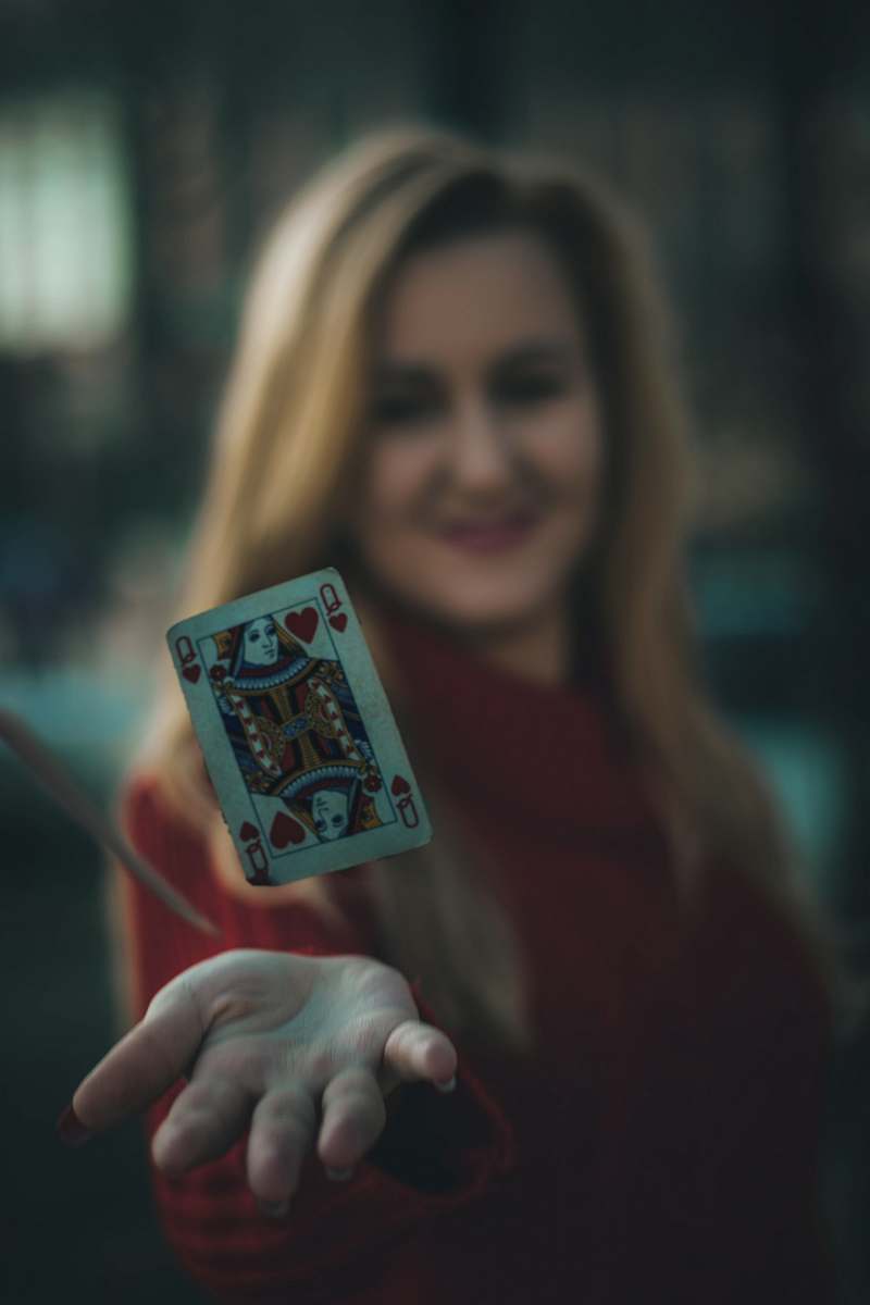 human time lapse photo of queen of hearts playing card near woman's palm people