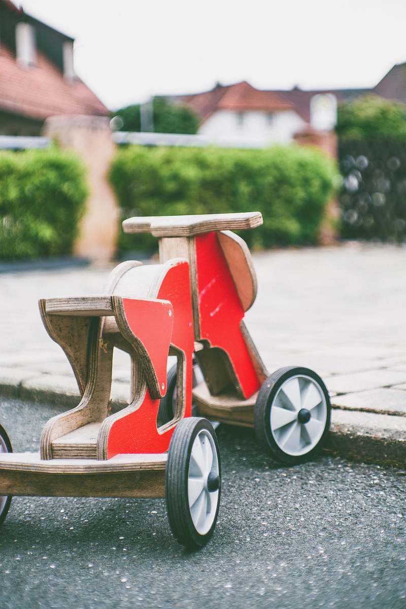 people toddler's red and brown wooden ride-on toy on concrete pavement human