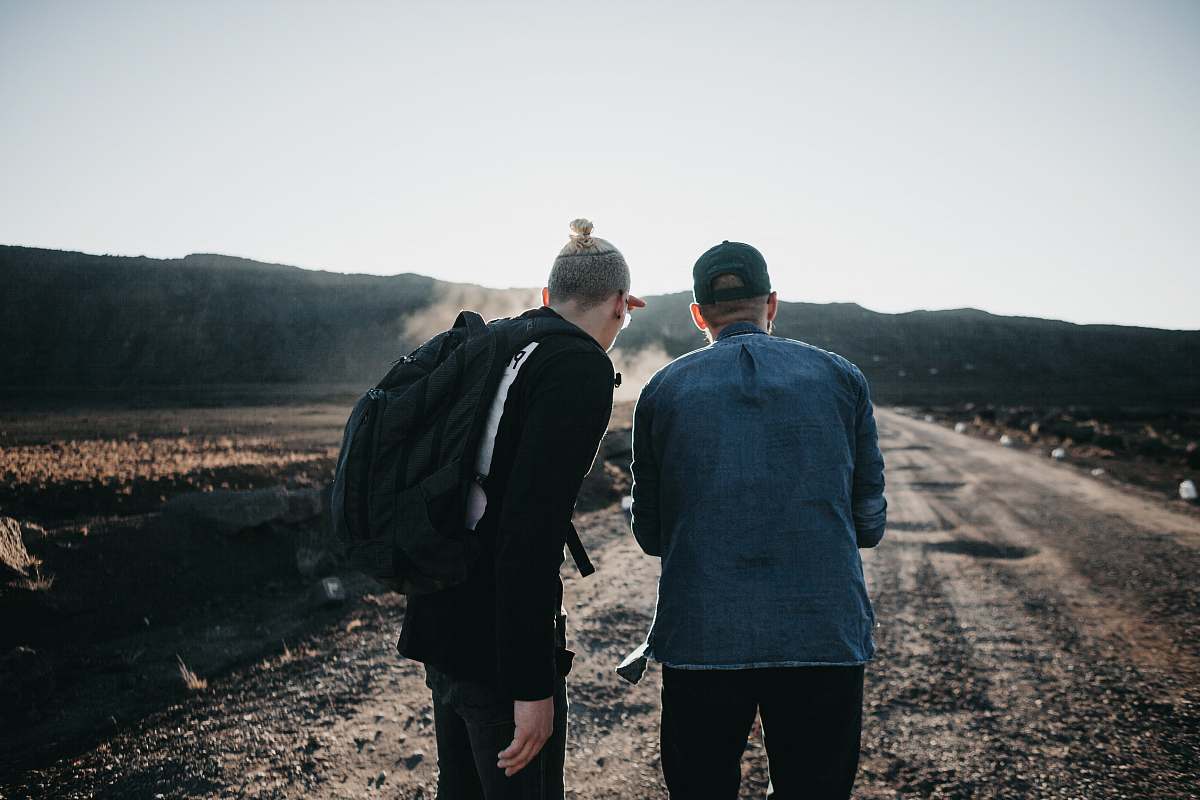 human two men standing on brown pathway people