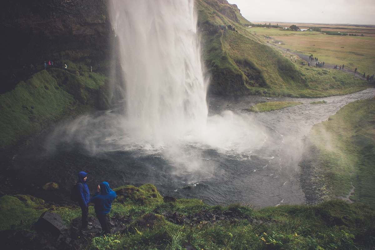 people two person wearing blue hoodie standing on ground in front of waterfalls human