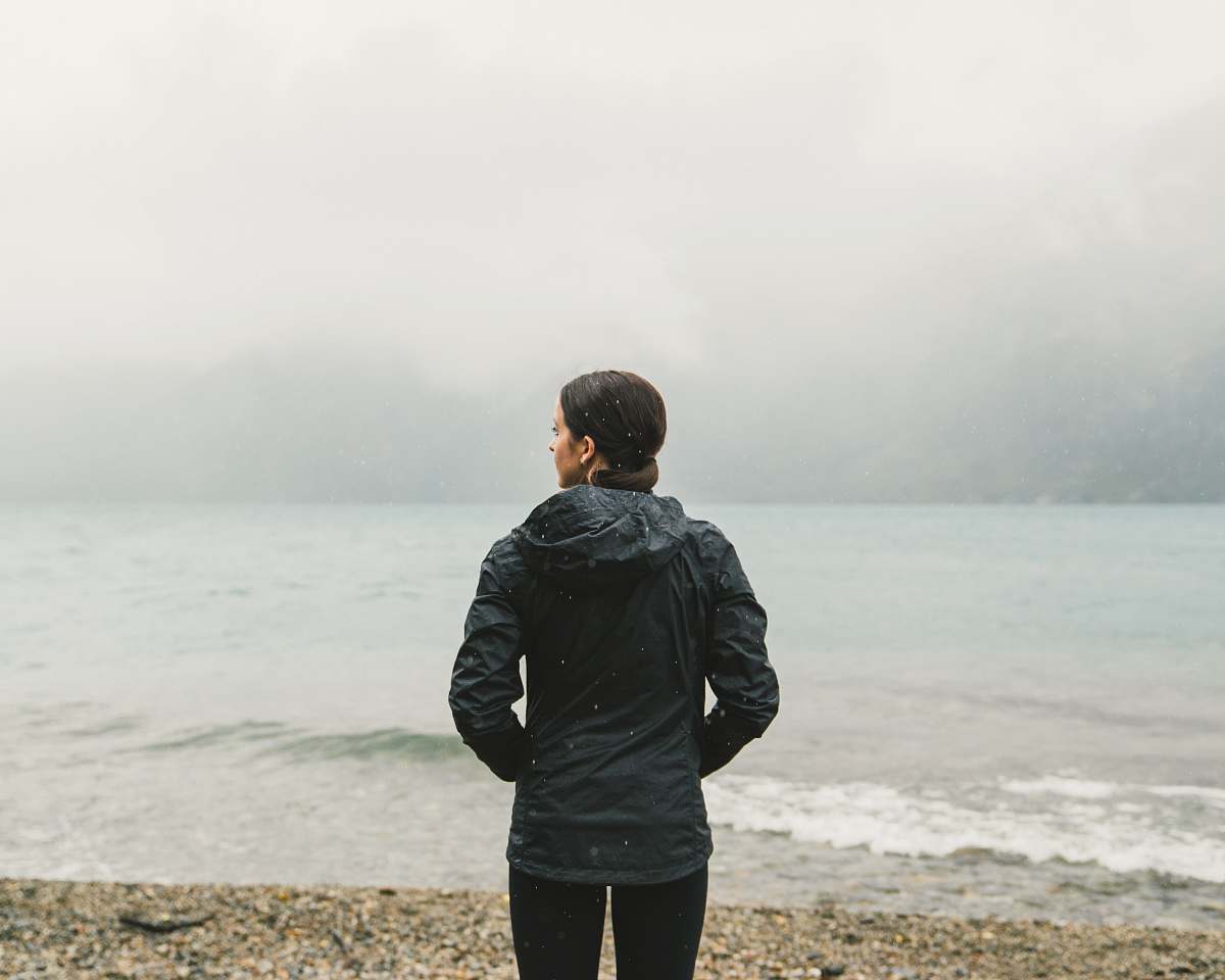 This captivating image features a woman standing on a serene beach, gazing thoughtfully at the vast ocean before her. The soft waves and gentle breeze create a tranquil atmosphere, perfect for conveying themes of reflection, peace, and connection with nature. Ideal for use in wellness, travel, or inspirational content, this visual encapsulates the beauty of solitude and the allure of coastal landscapes.