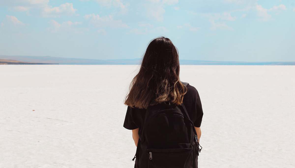 human woman facing white field with backpack at daytime people