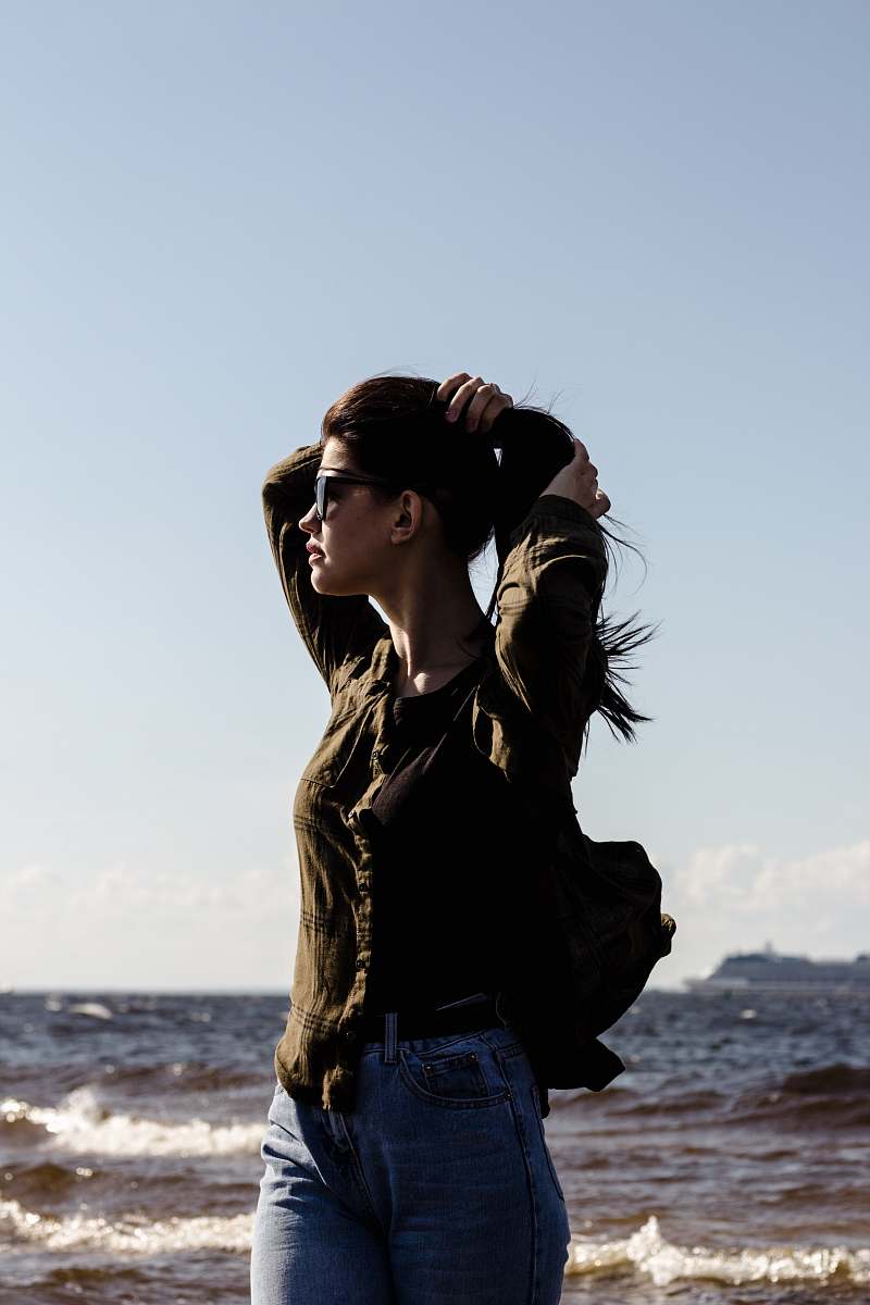 human woman fixing hair while standing near body of water people