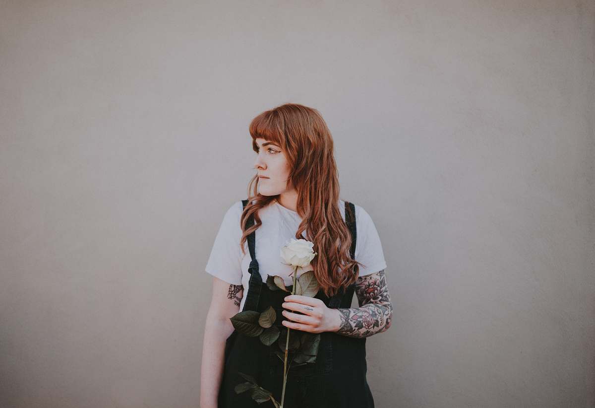 human woman holding white rose looking at her left side people
