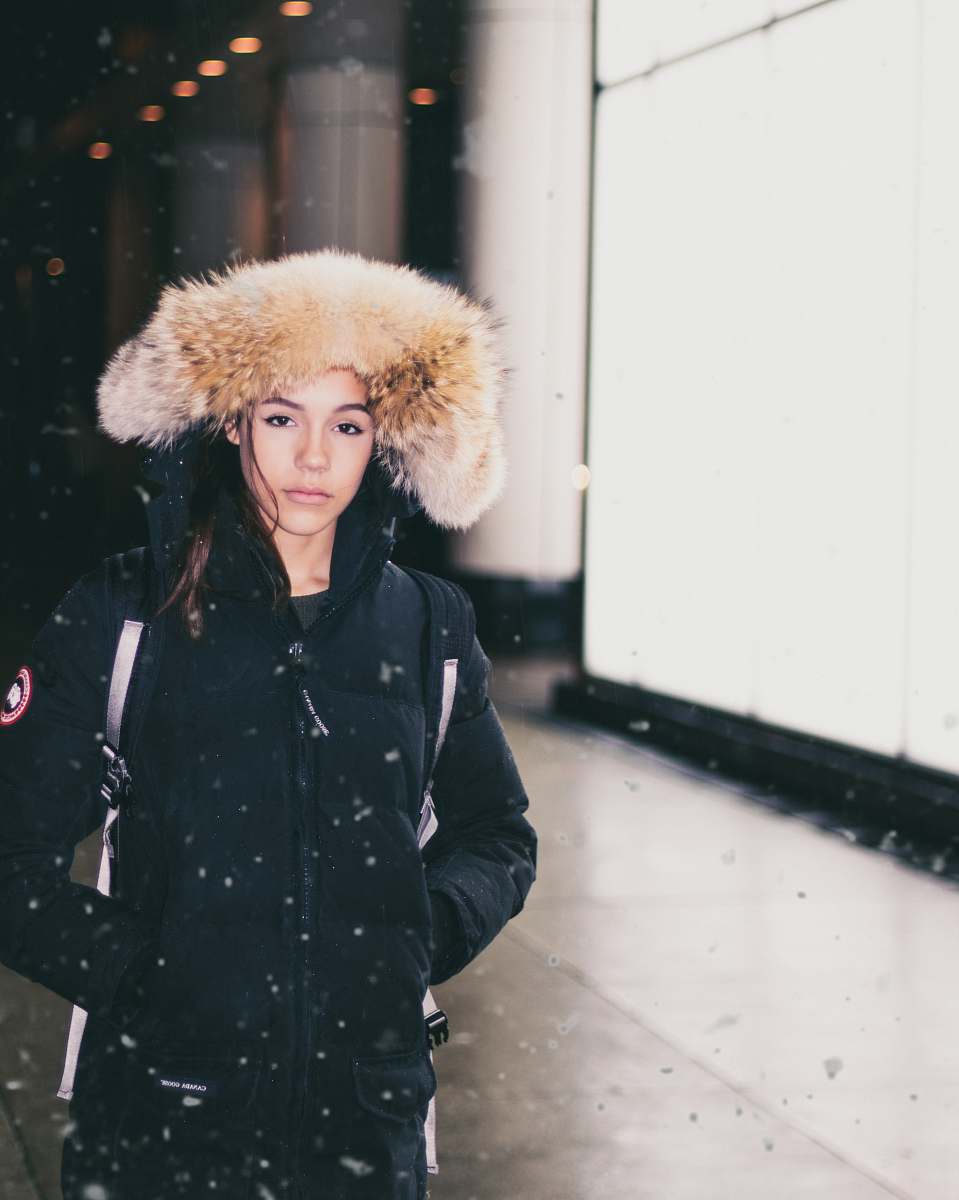 people woman in black parka jacket standing while snowing human