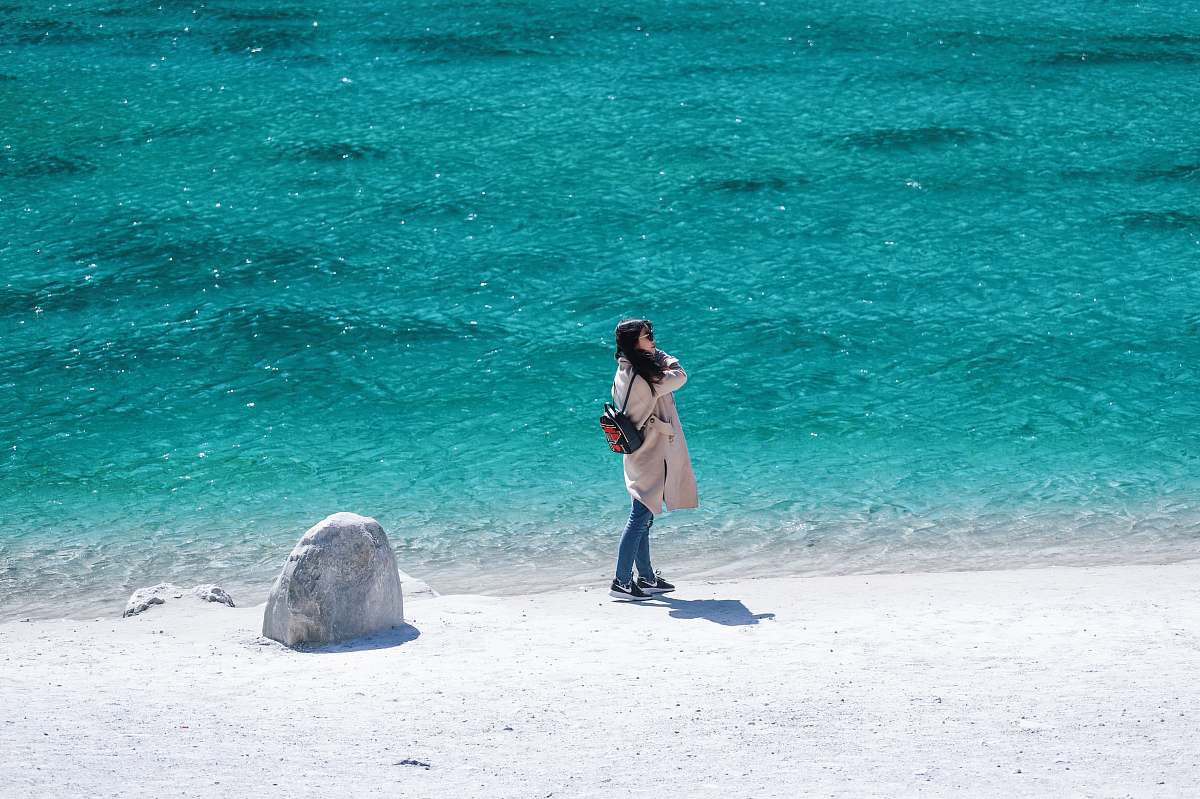 human woman in brown coat beside body of water during daytime people