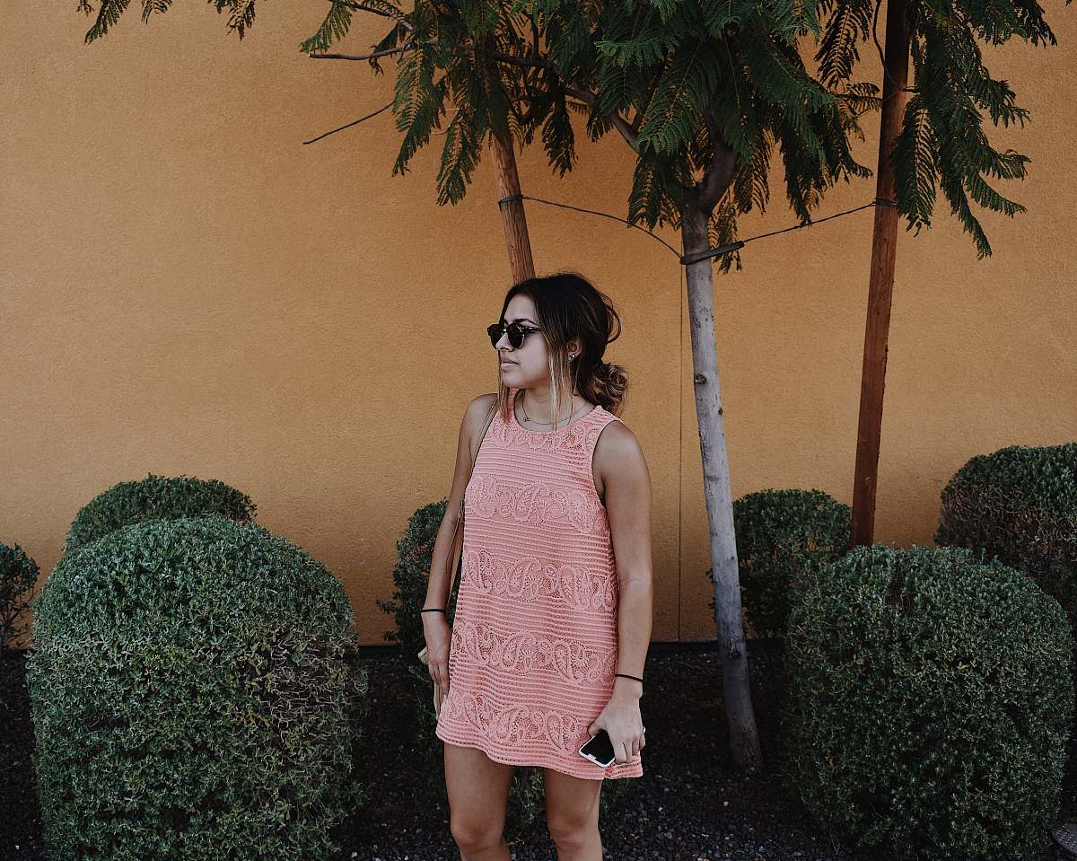 people woman in pink sleeveless shift mini dress standing near bushes at daytime human