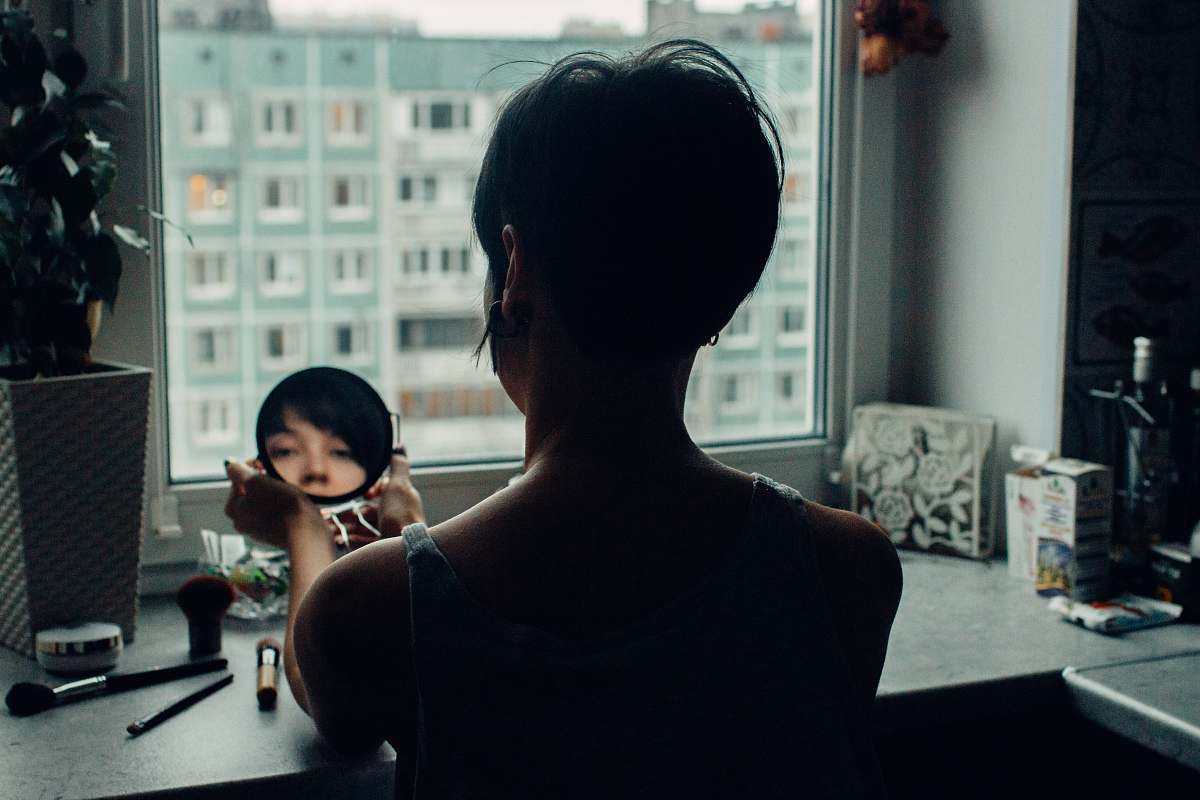 human woman looking at mirror beside window people