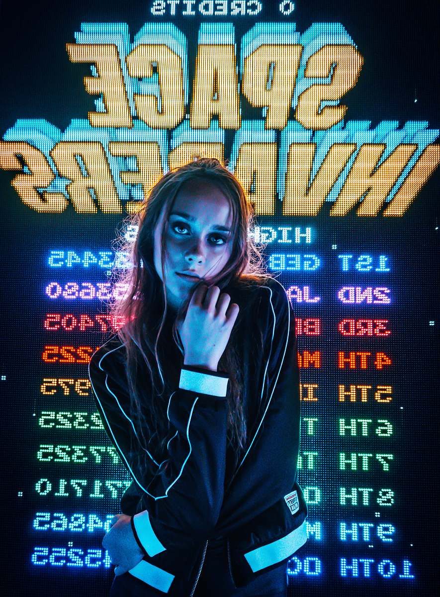 people woman posing for photo in front of Space Invaders scoreboard human