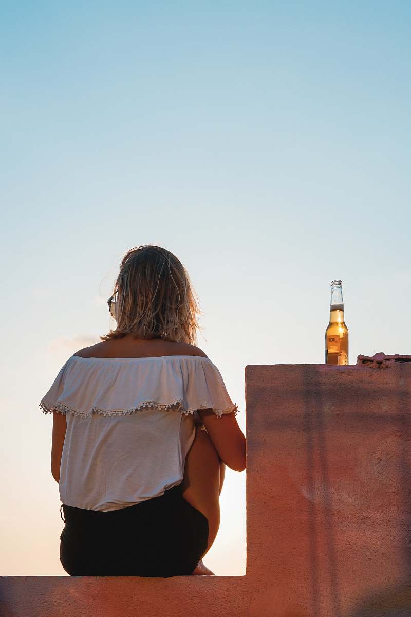 human woman sitting on concrete wall back