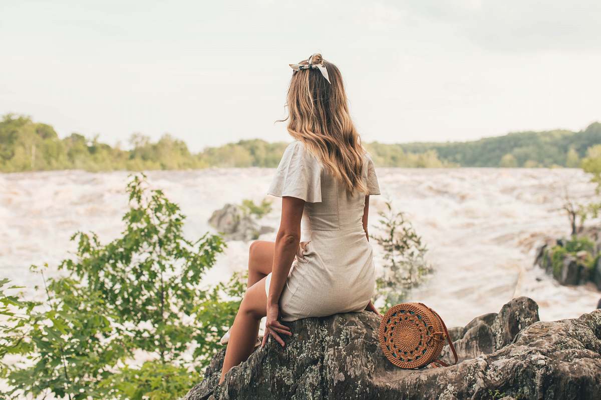 people woman sitting on rock beside body of water human