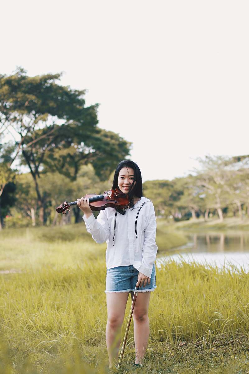 human woman standing holding violin near river people