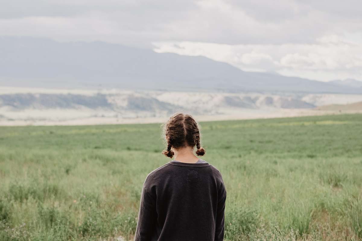 field woman standing in front of green grass field during daytime outdoors