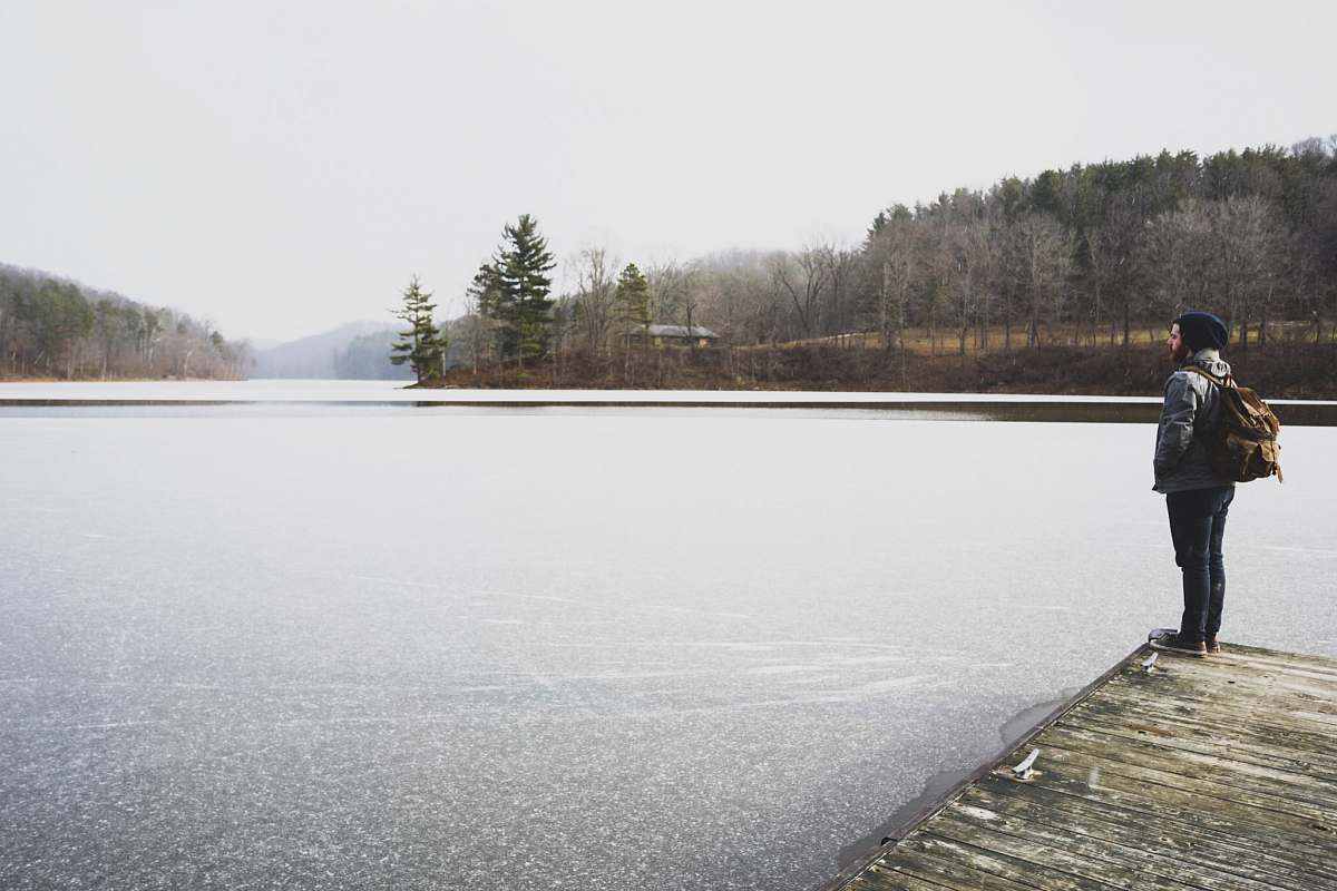 human woman standing in front of lake while staring at it people