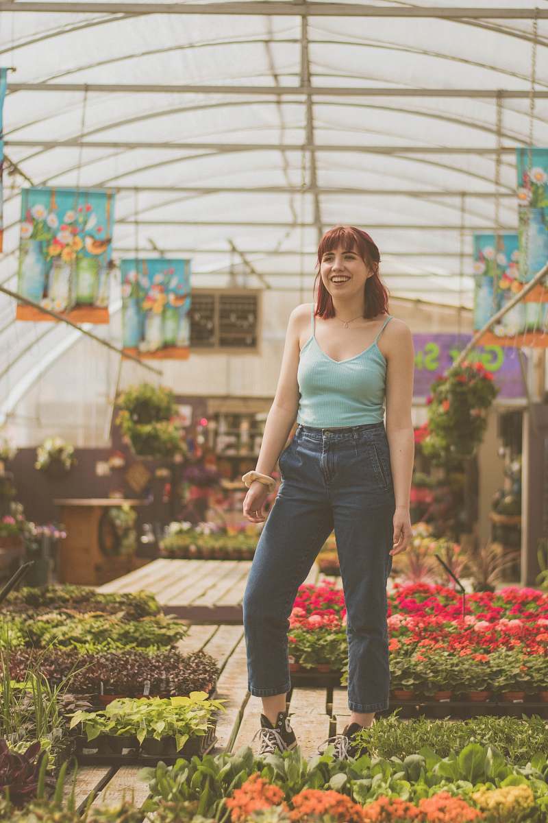 human woman standing near flower pots inside greenhouse people